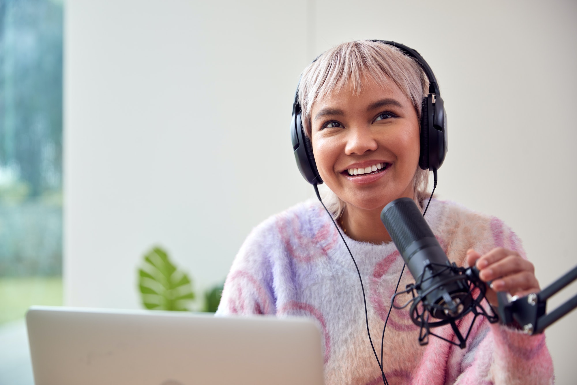 woman-recording-podcast-or-broadcasting-on-radio-in-studio-at-home-with-laptop.jpg